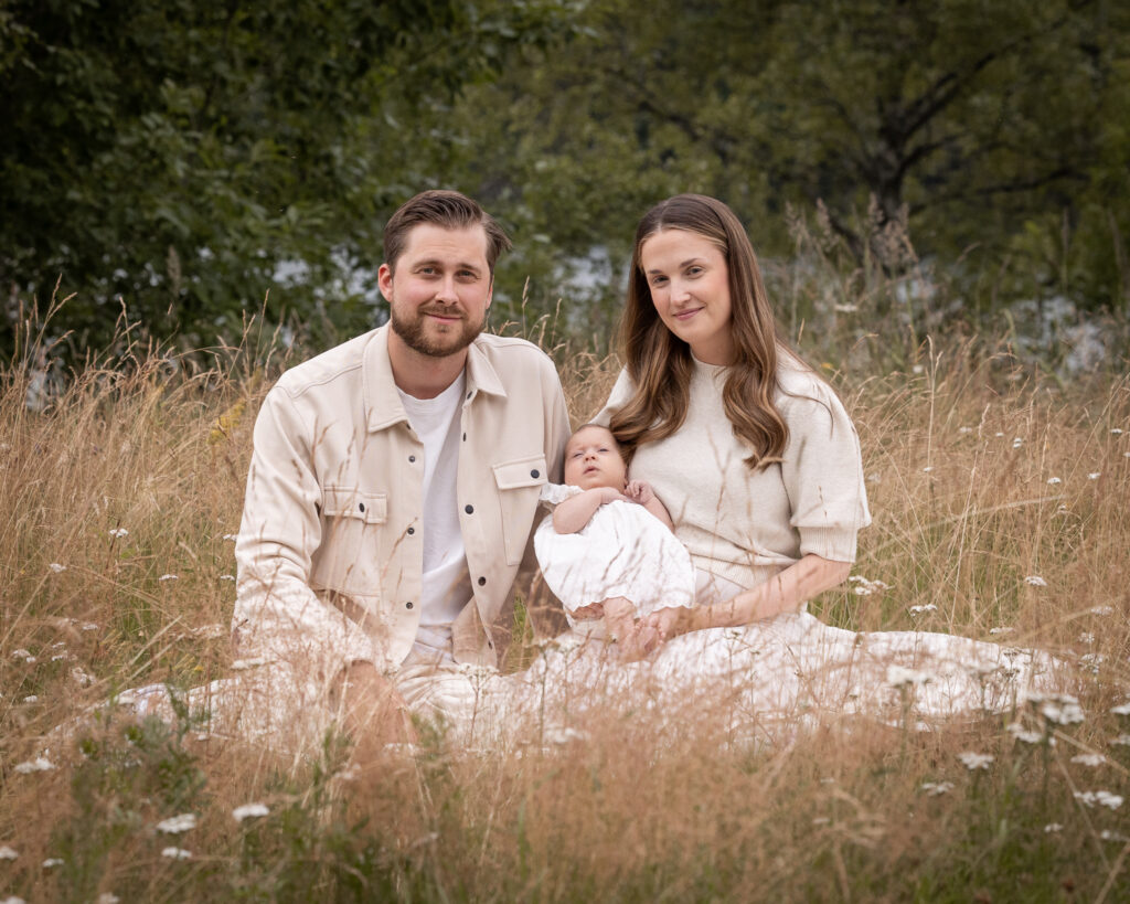 Familjeporträtt med nyfödd i sommarängen